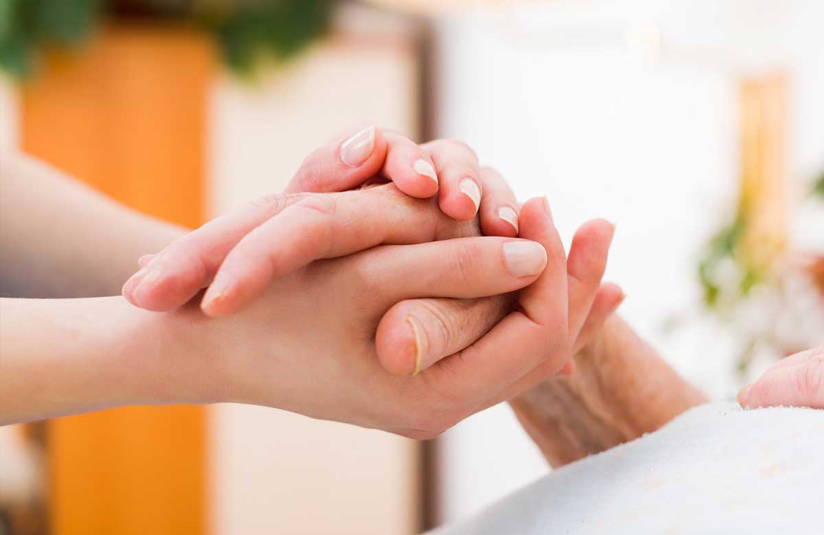 Carer holding woman's hand