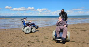 Care home residents enjoying beach wheelchairs at portobello